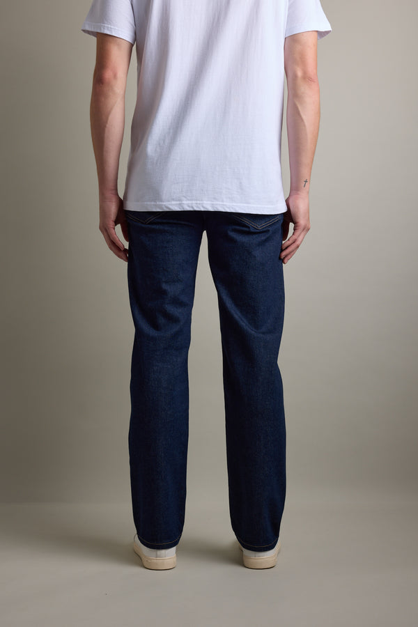 Person stands facing away in Barkers Drifter Denim Relax Jean, white T-shirt, and white shoes.