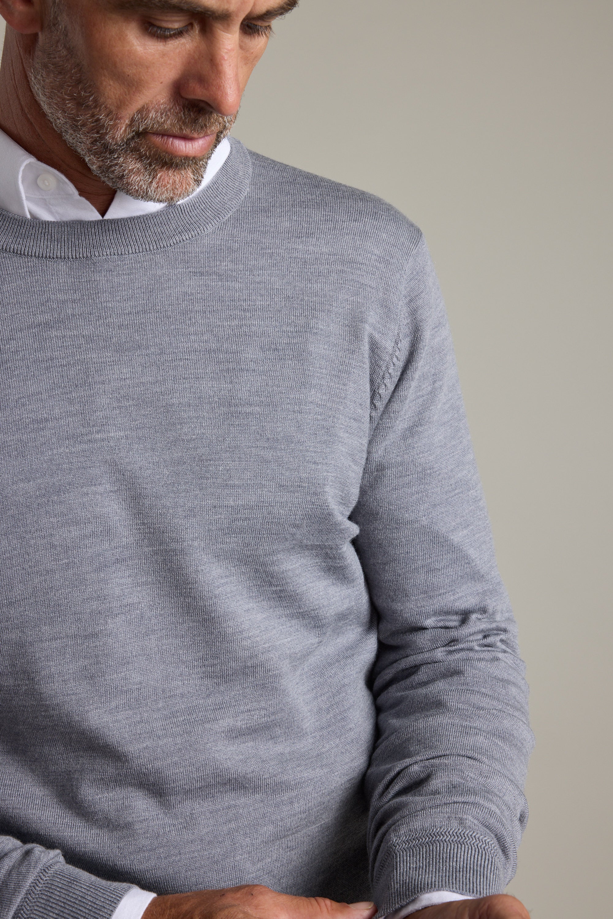 Man wears Barkers Skyland ZQrx Merino Crew, white shirt, looking down, chest up.