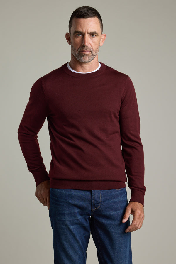 Man in a Barkers Skyland ZQrx Merino Crew sweater and jeans stands against a plain background.