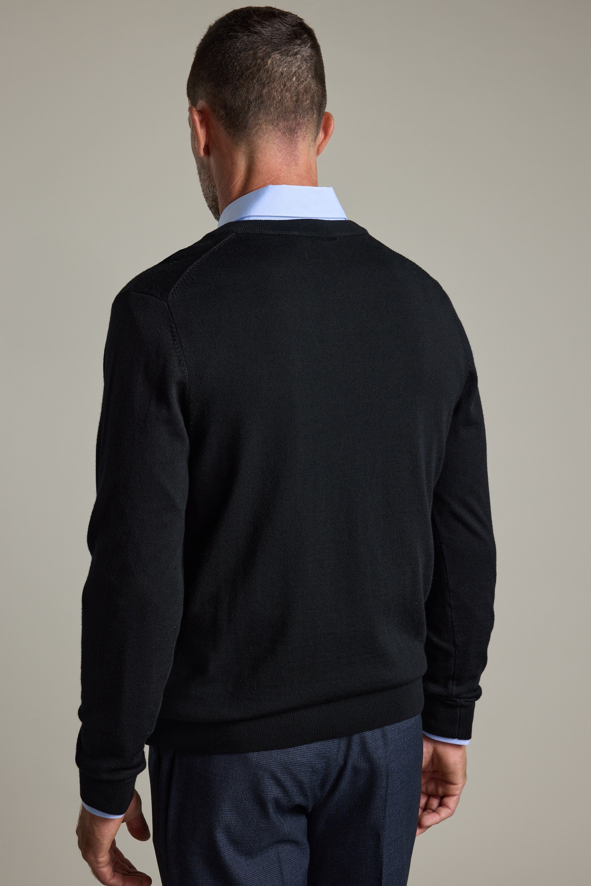 A man in a Barkers Skyland ZQrx Merino Vee black sweater and blue shirt, seen from behind.