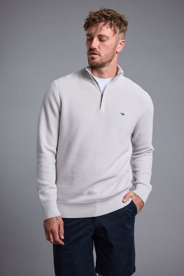 Man in a Barkers Gaston Cotton 1/4 Zip Sweater and navy shorts against a gray background.