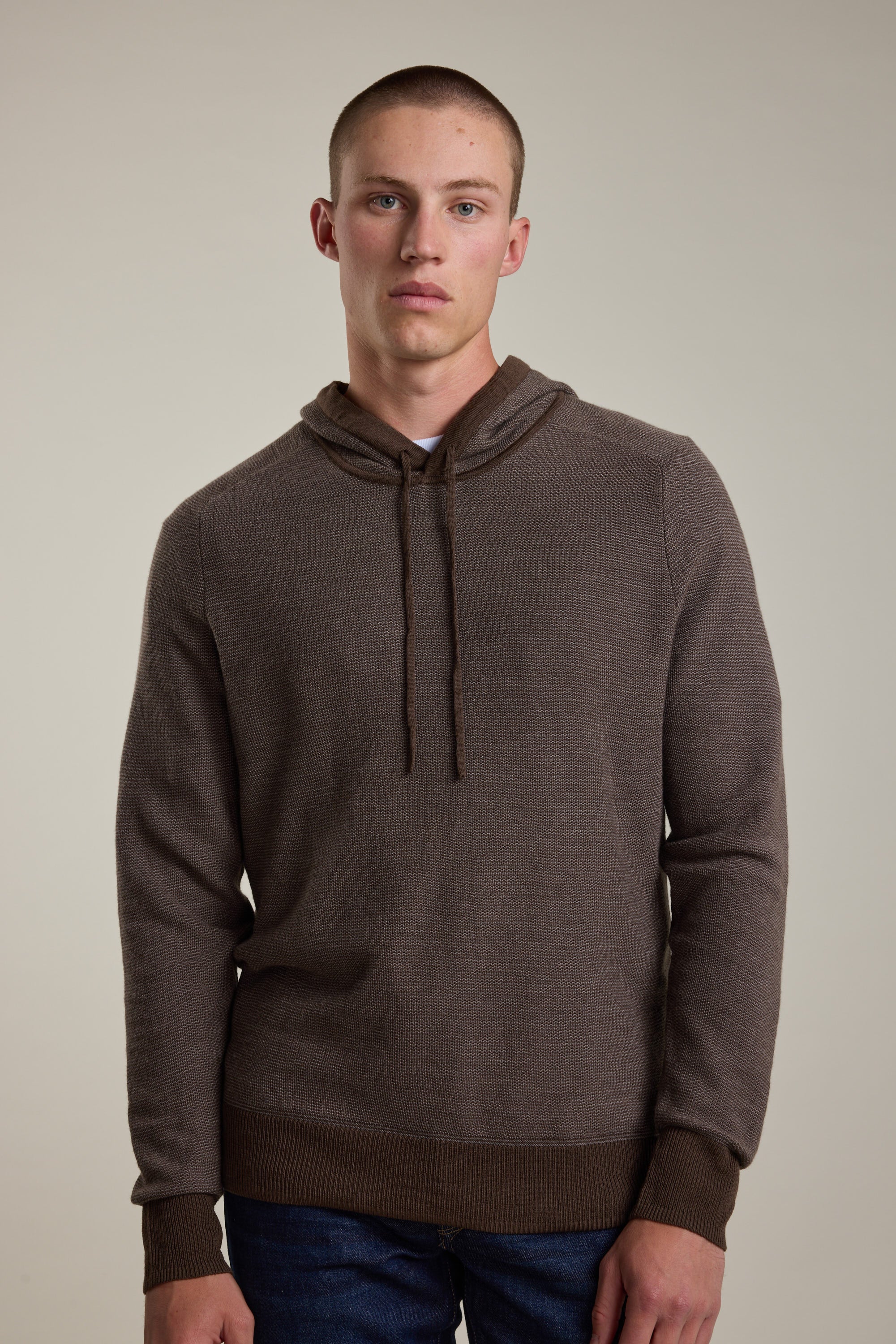 A young man with short hair wears the Barkers Roxbury Merino Hoody over a white shirt, standing against a neutral background and looking directly at the camera with a neutral expression.