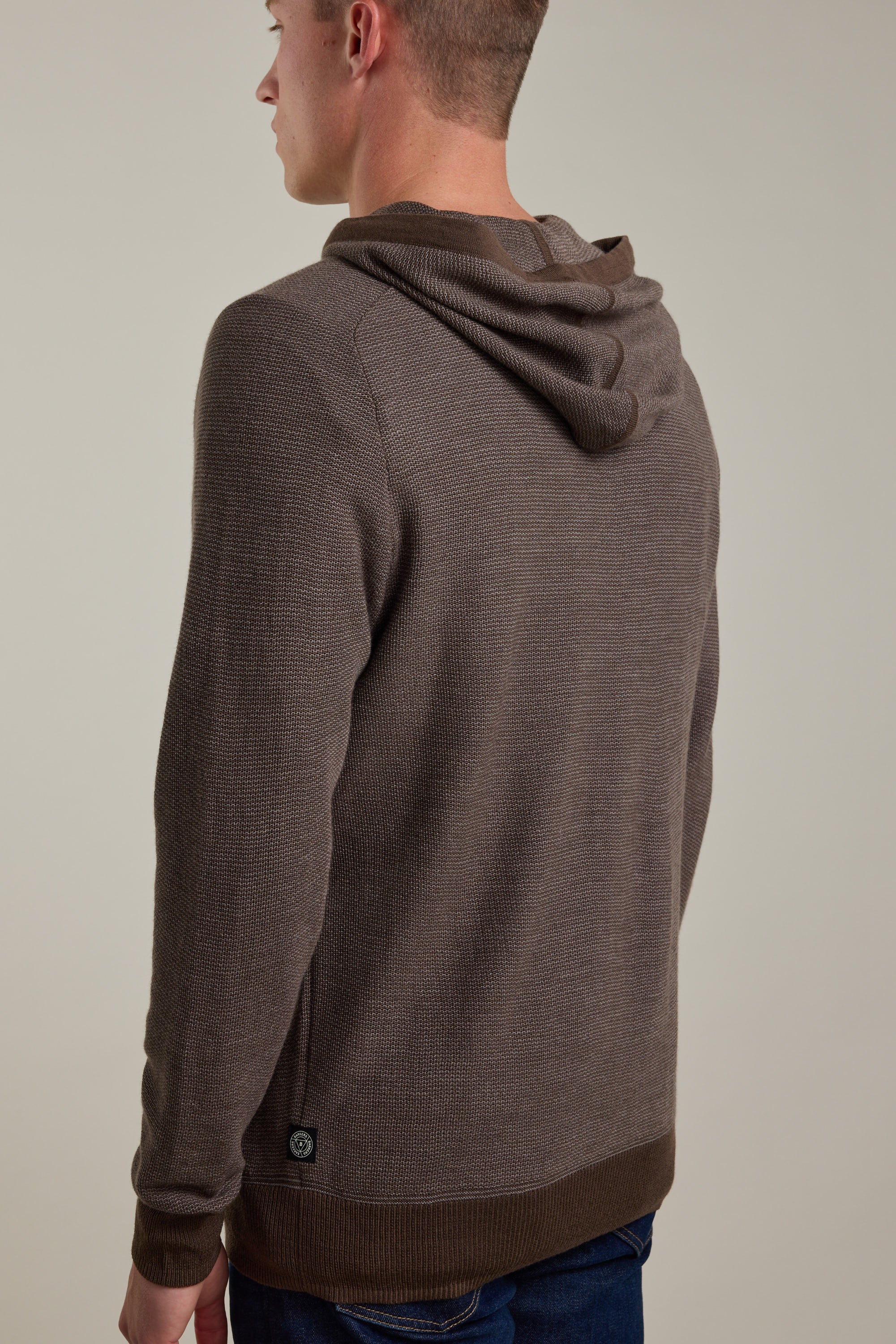 A person is shown from the back wearing the Barkers Roxbury Merino Hoody against a plain light background. The lightweight sweater features a textured knit pattern and ribbed cuffs and hem.