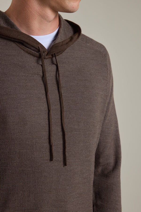 A person wears the Barkers Roxbury Merino Hoody in brown textured 100% merino wool, layered over a white shirt. Shown from shoulders to mid-chest, the hoodie's drawstrings hang down against a plain, neutral background.