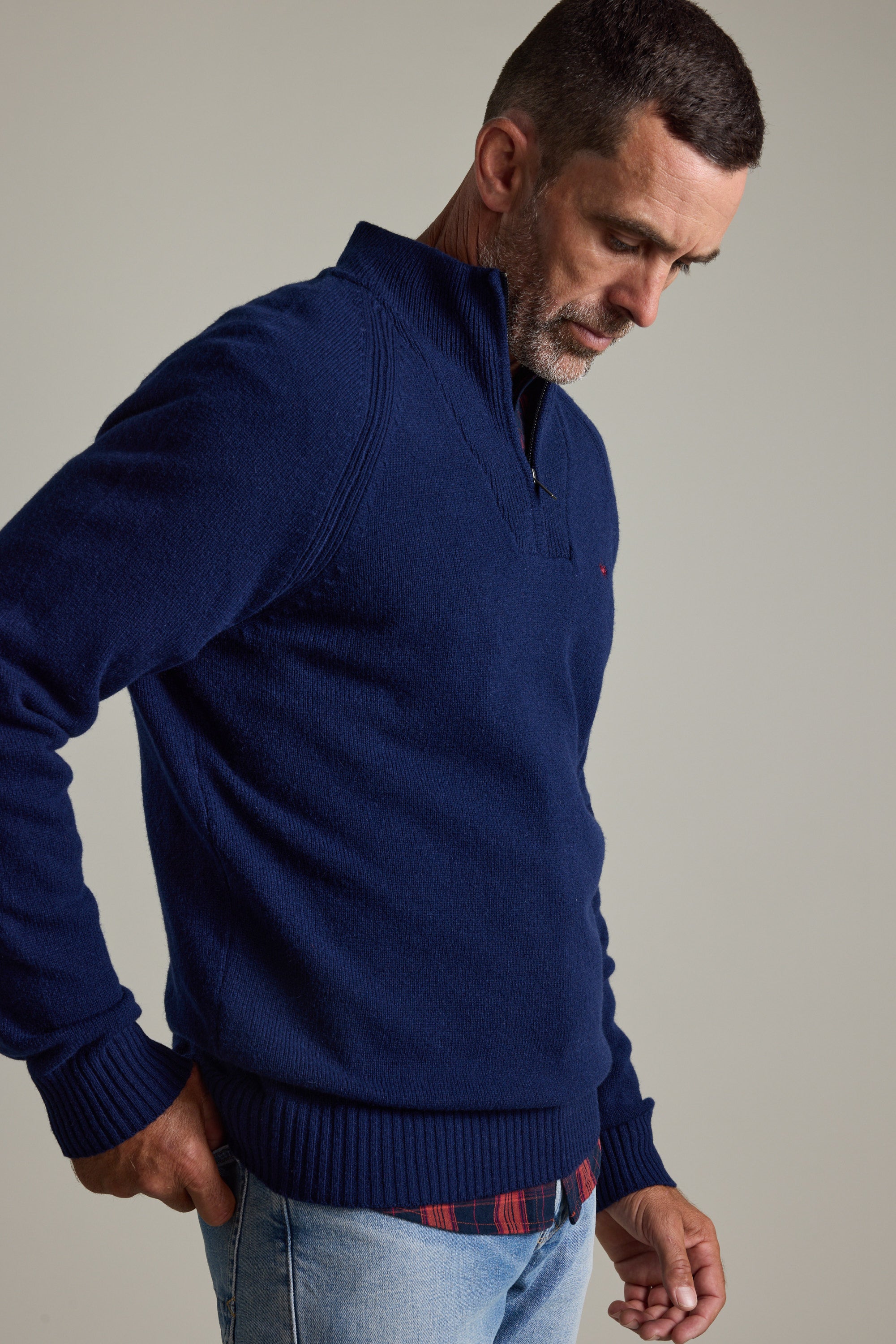 Man wears Barkers Rowley Woollen 1/4 Zip sweater and jeans, looking down with hand in pocket.