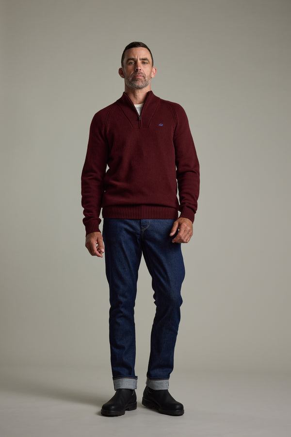 A man wears the Barkers Rowley Woollen 1/4 Zip with jeans against a plain gray background.