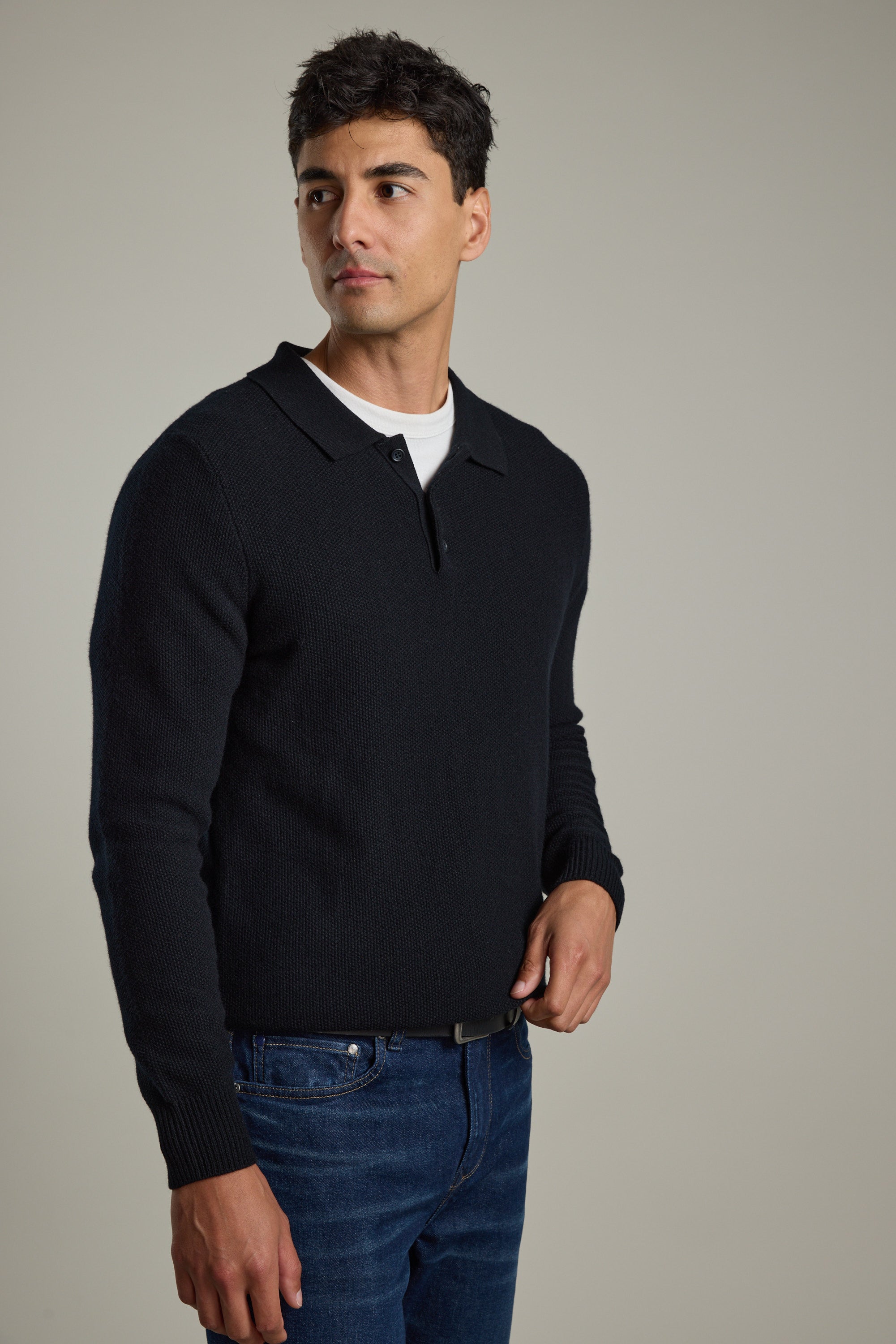 Man in Barkers Ainsley Woollen Long Sleeve Polo and jeans stands against a plain background.