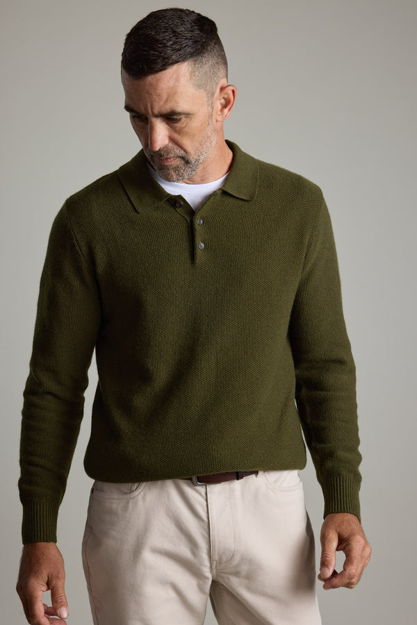 Man wearing Barkers Ainsley Woollen Long Sleeve Polo in olive green and beige pants, looking down.