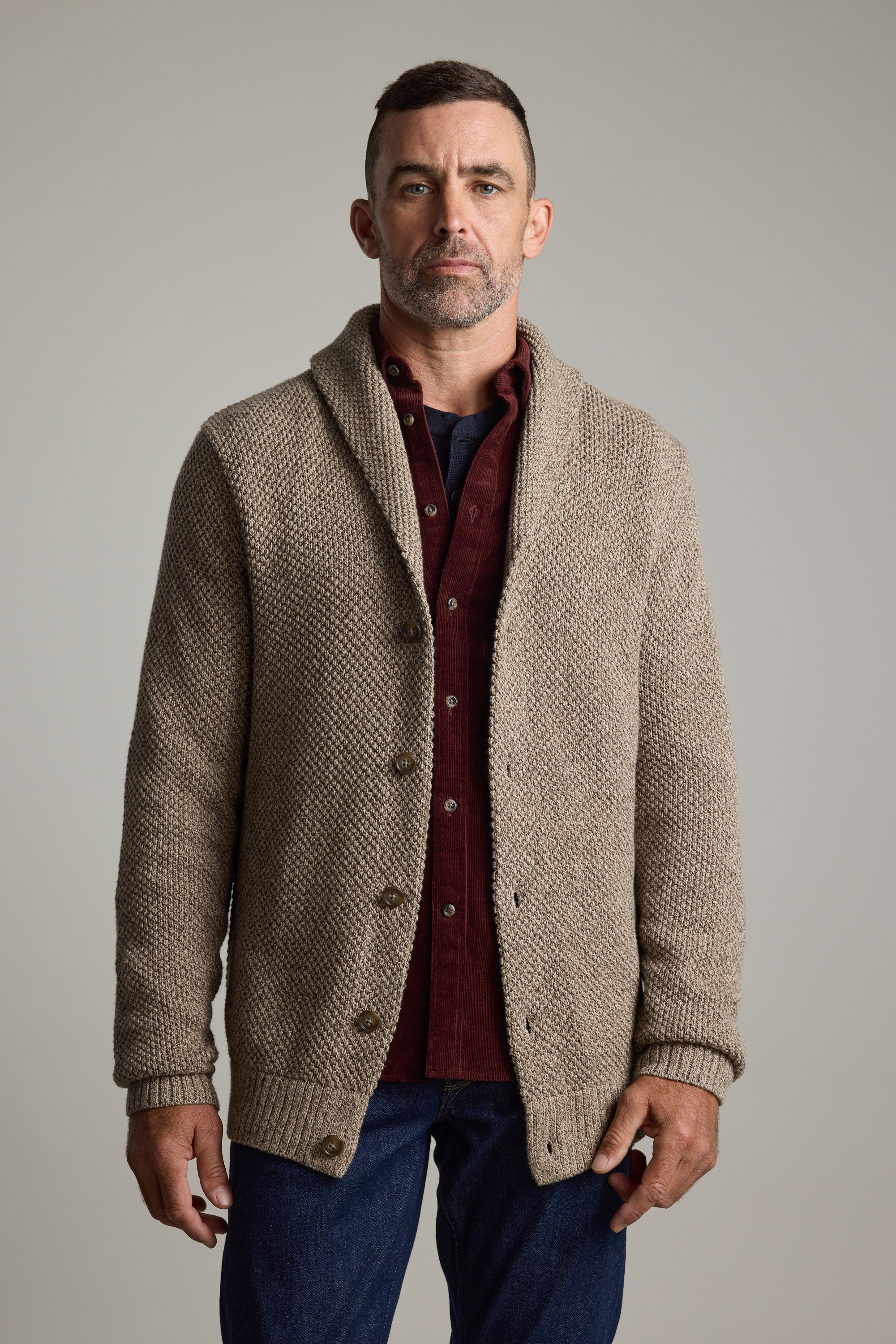 Man in Barkers Rudder Cotton Shawl Cardi over a burgundy shirt and jeans, ideal for winter.