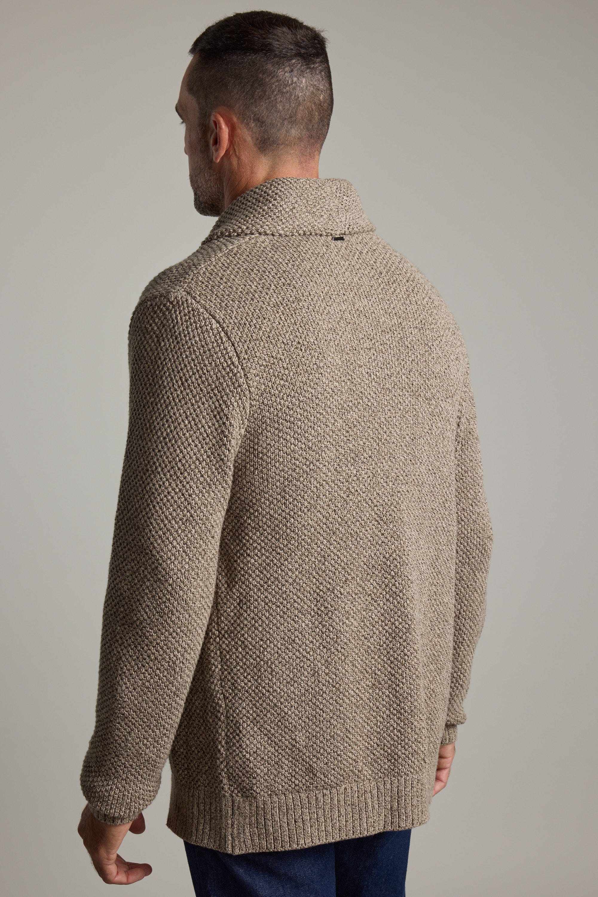 Man wears Barkers Rudder Cotton Shawl Cardi, ideal for winter layering, facing away.