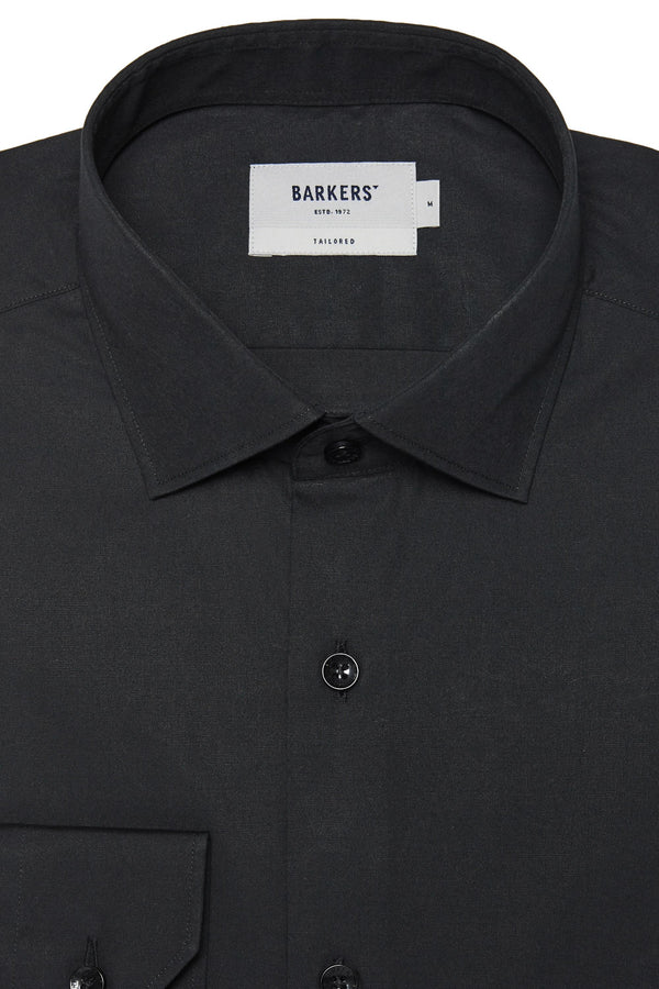 Close-up of the Barkers Tribeca Reg Cuff Shirt in black, tailored fit with front buttons. A white label inside the collar reads Barkers. Part of a left chest pocket is visible.