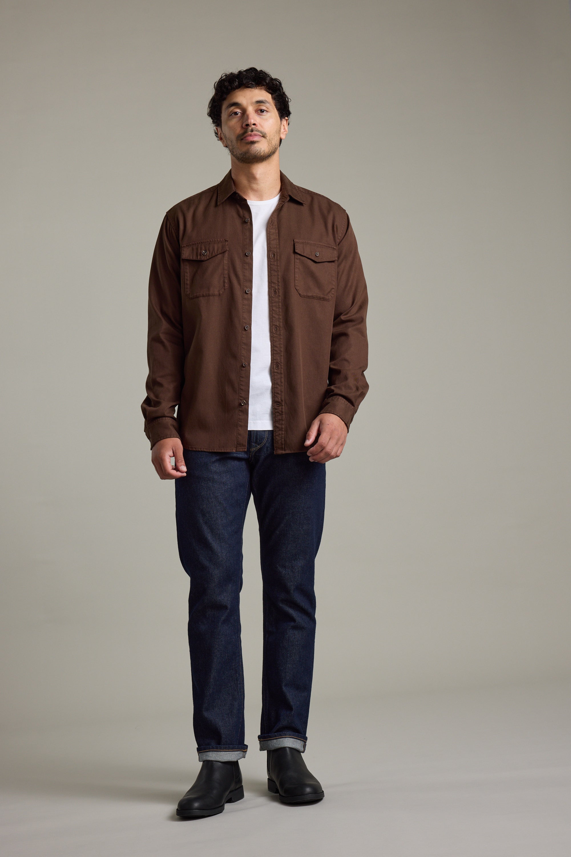 Man wears Barkers Darden Shirt, white tee, blue jeans, and black boots indoors.