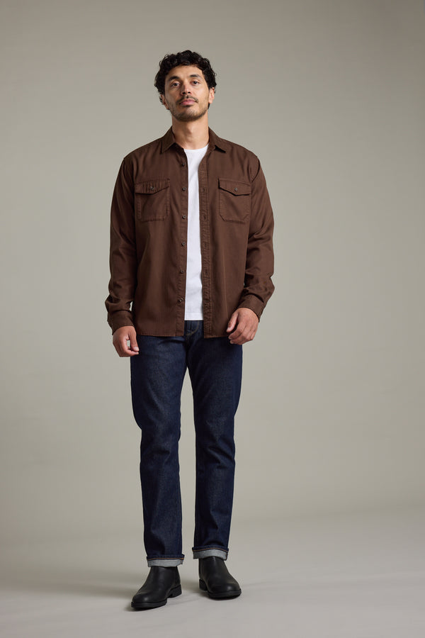 Man wears Barkers Darden Shirt, white tee, blue jeans, and black boots indoors.