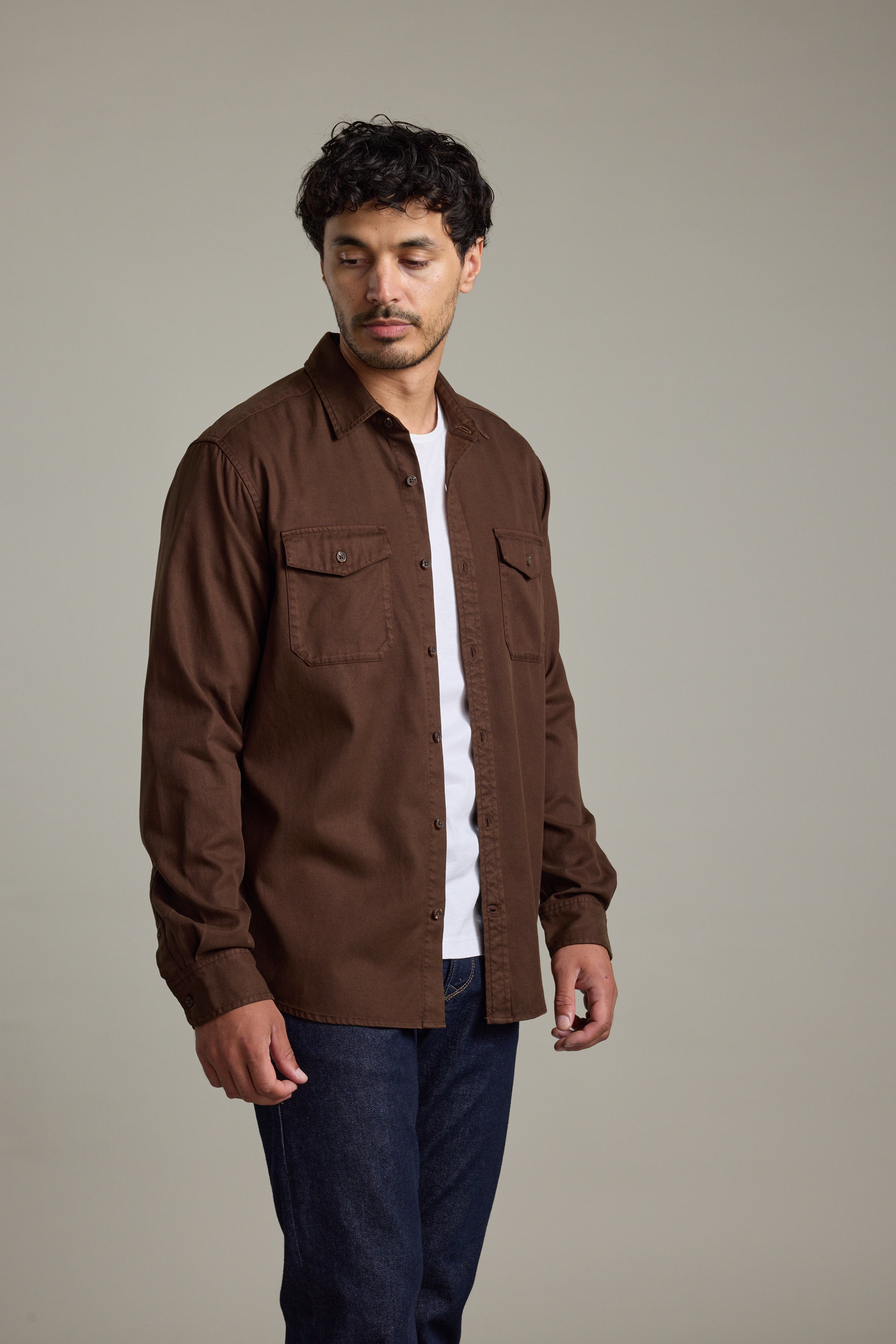 Man in a brown Barkers Darden Shirt over a white tee, looking down.