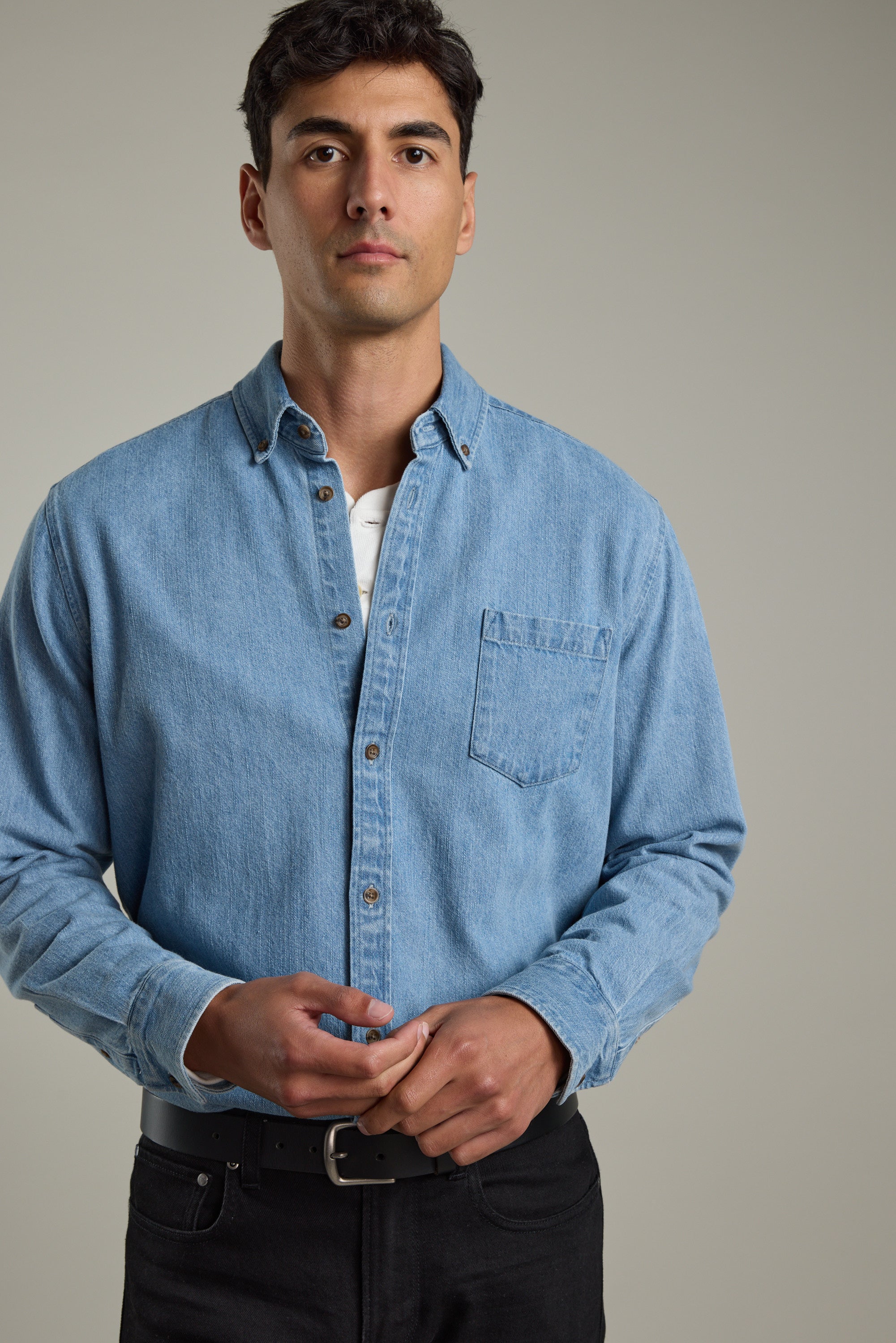 Man in a Barkers Avalon Denim Shirt and black pants stands against a plain background.