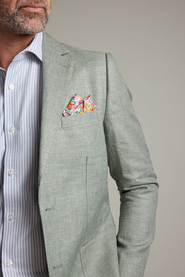 A man wears the Barkers Marion Texture Blazer with a floral pocket square and light blue striped shirt, shown from shoulders to waist against a plain background—a stylish choice for summer occasions.
