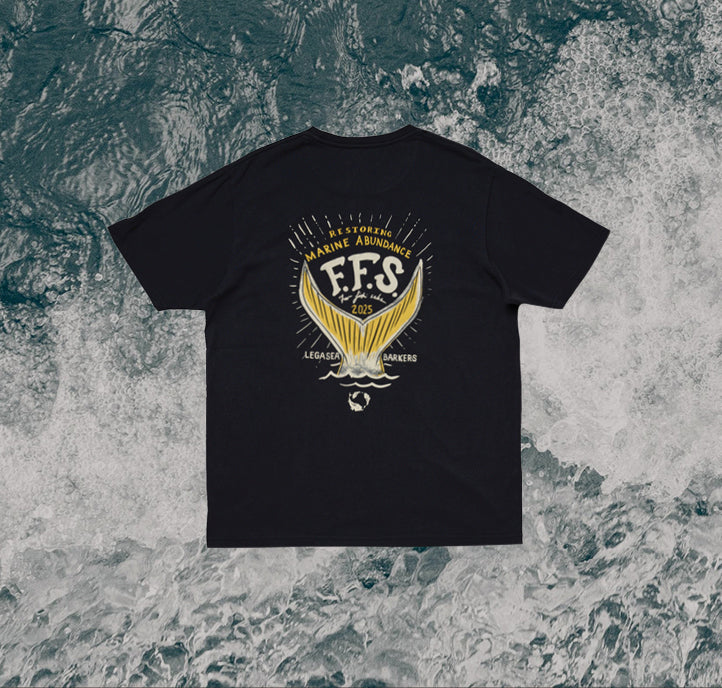 A black t-shirt with a large gold and white graphic on the back, featuring two fish tails, the text “Restoring Marine Abundance E.F.S. 2025” and “Legacy Makers,” displayed on an ocean background.