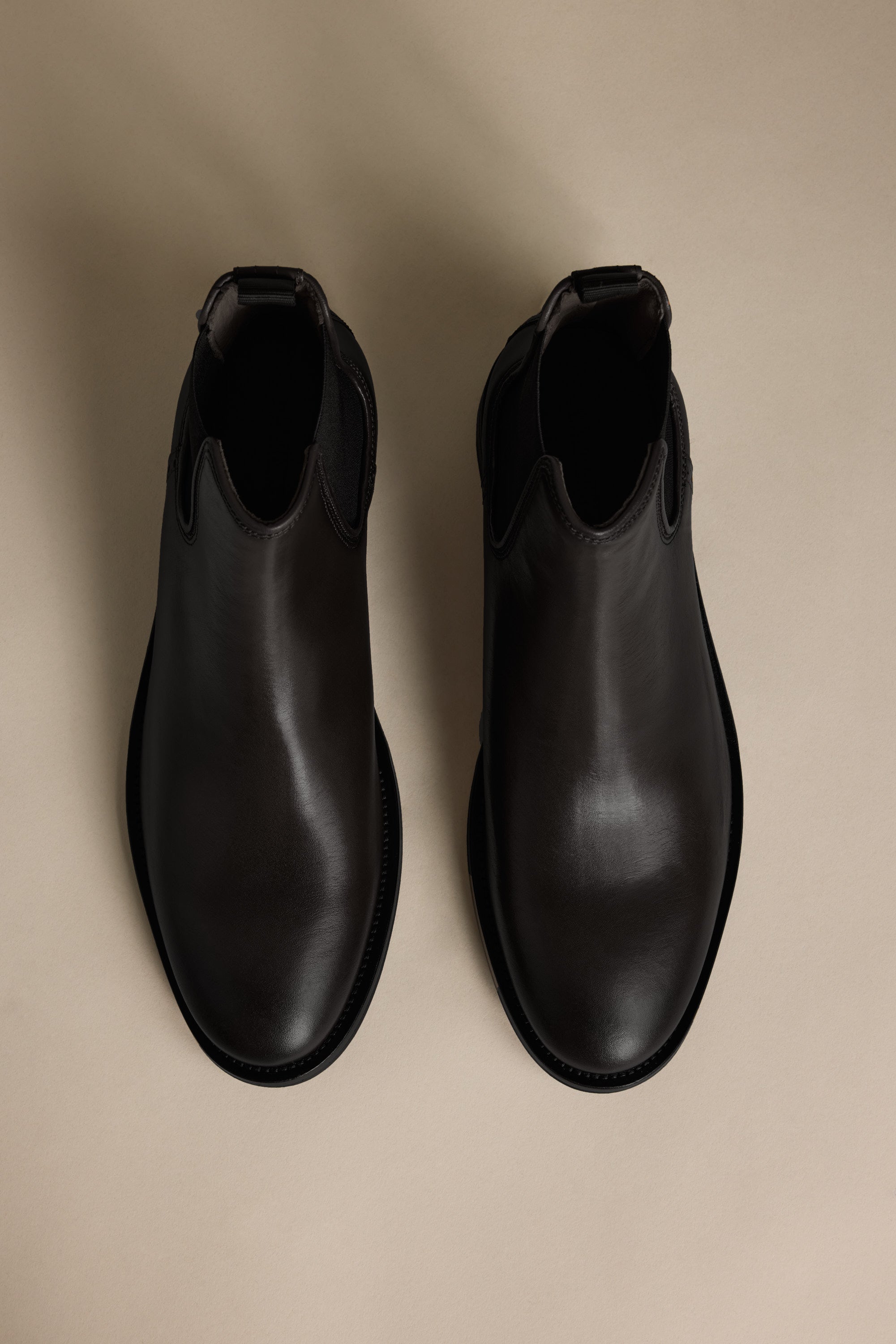 The Barkers Peter Chelsea Boot in black leather on a beige background, viewed from above.