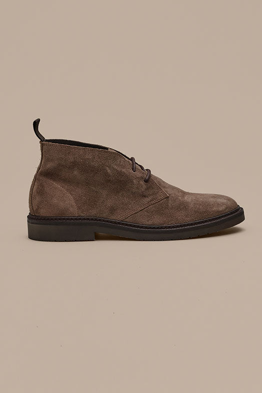 The Barkers Howarth Desert Boot, shown in side profile on a beige background, features brown suede crafted from responsibly sourced leather with black laces and a black sole—timeless Portuguese style and quality.