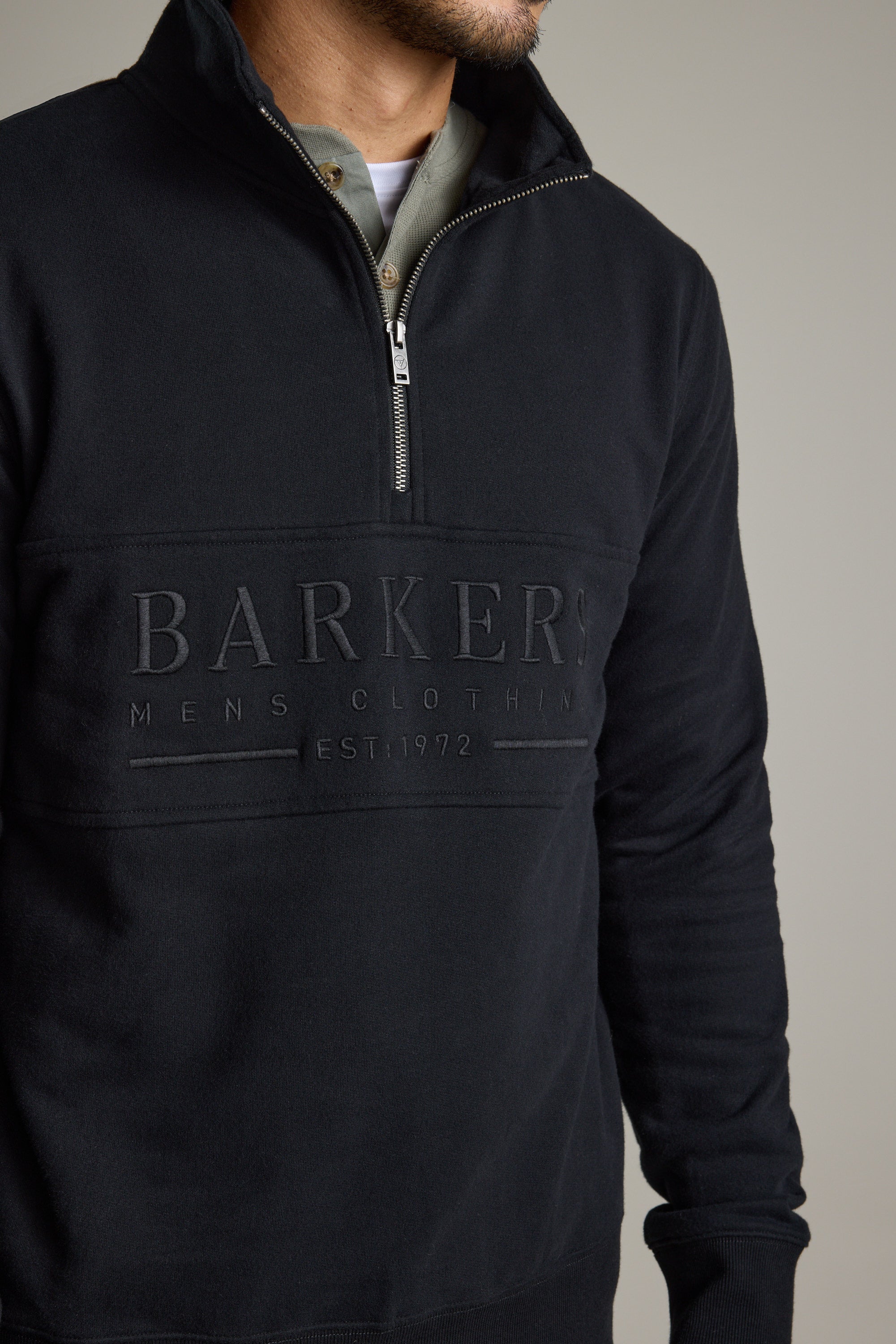 Man wearing a Barkers Heritage 1/4 Zip sweater with embossed logo over a collared shirt.