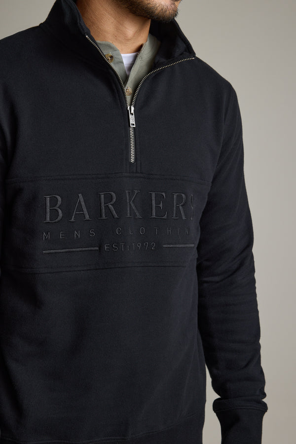 Man wearing a Barkers Heritage 1/4 Zip sweater with embossed logo over a collared shirt.