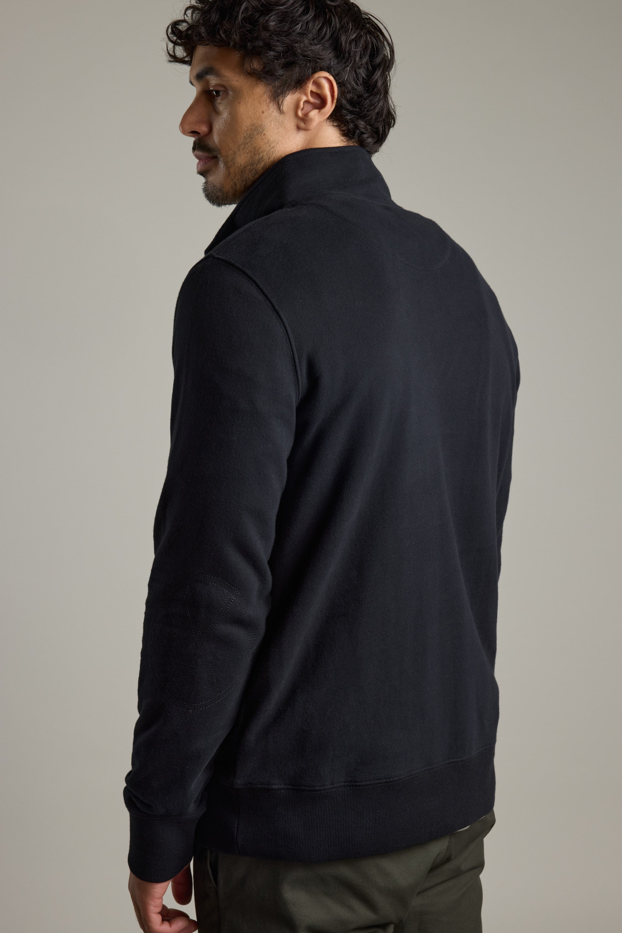 Man in a Barkers Heritage 1/4 Zip facing away, looking to the side against a plain background.