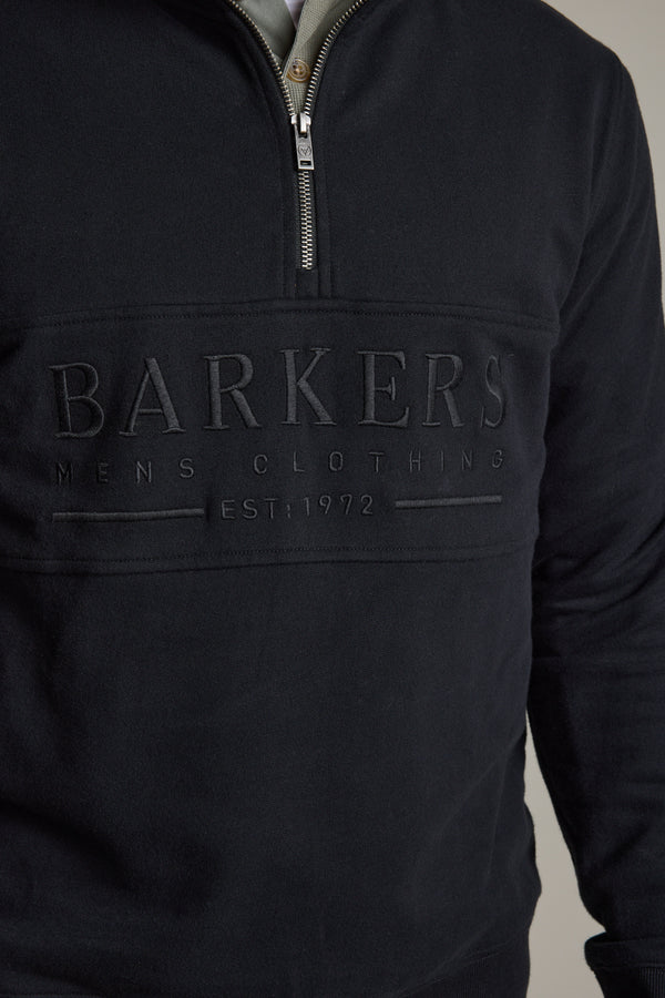 Man wears a Barkers Heritage 1/4 Zip sweater in black, crafted from premium French terry.