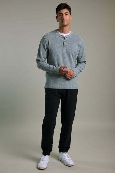 Man in a gray henley, Barkers Organic Classic Print Track Pant, and white sneakers.
