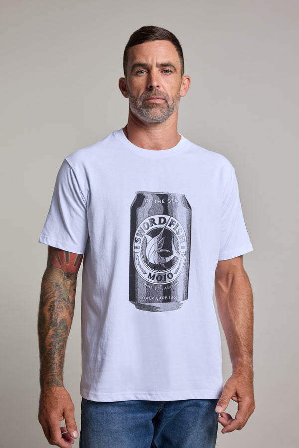 A man with short dark hair and a trimmed beard wears the Swordfish Mojo Beercan Tee, a white organic cotton shirt by Swordfish Mojo, featuring a bold black can graphic. Visible tattoos are on his right arm as he stands against a plain light background.