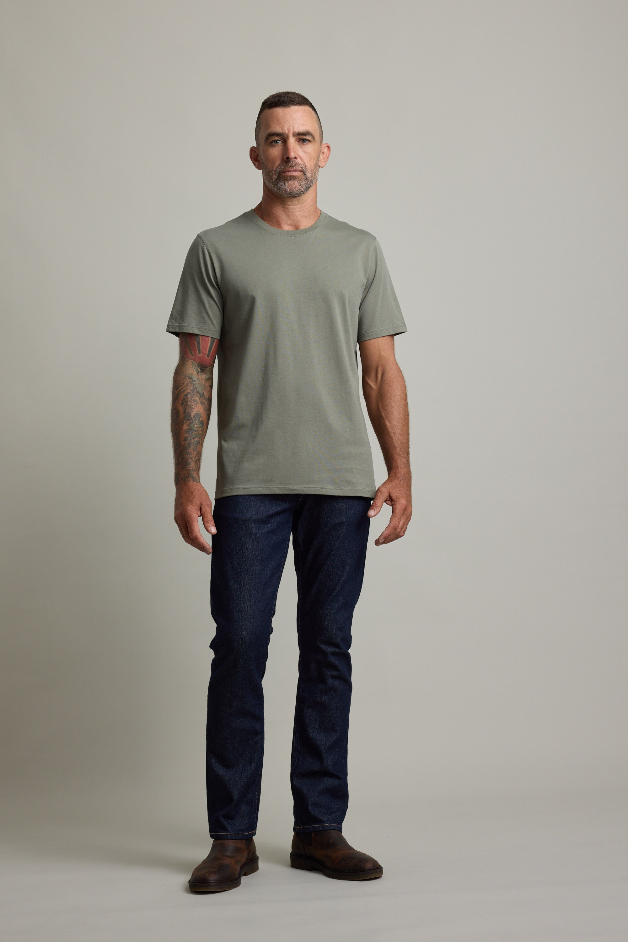 Man wears Barkers Good Earth Cotton Essential Tee in green against a neutral background.
