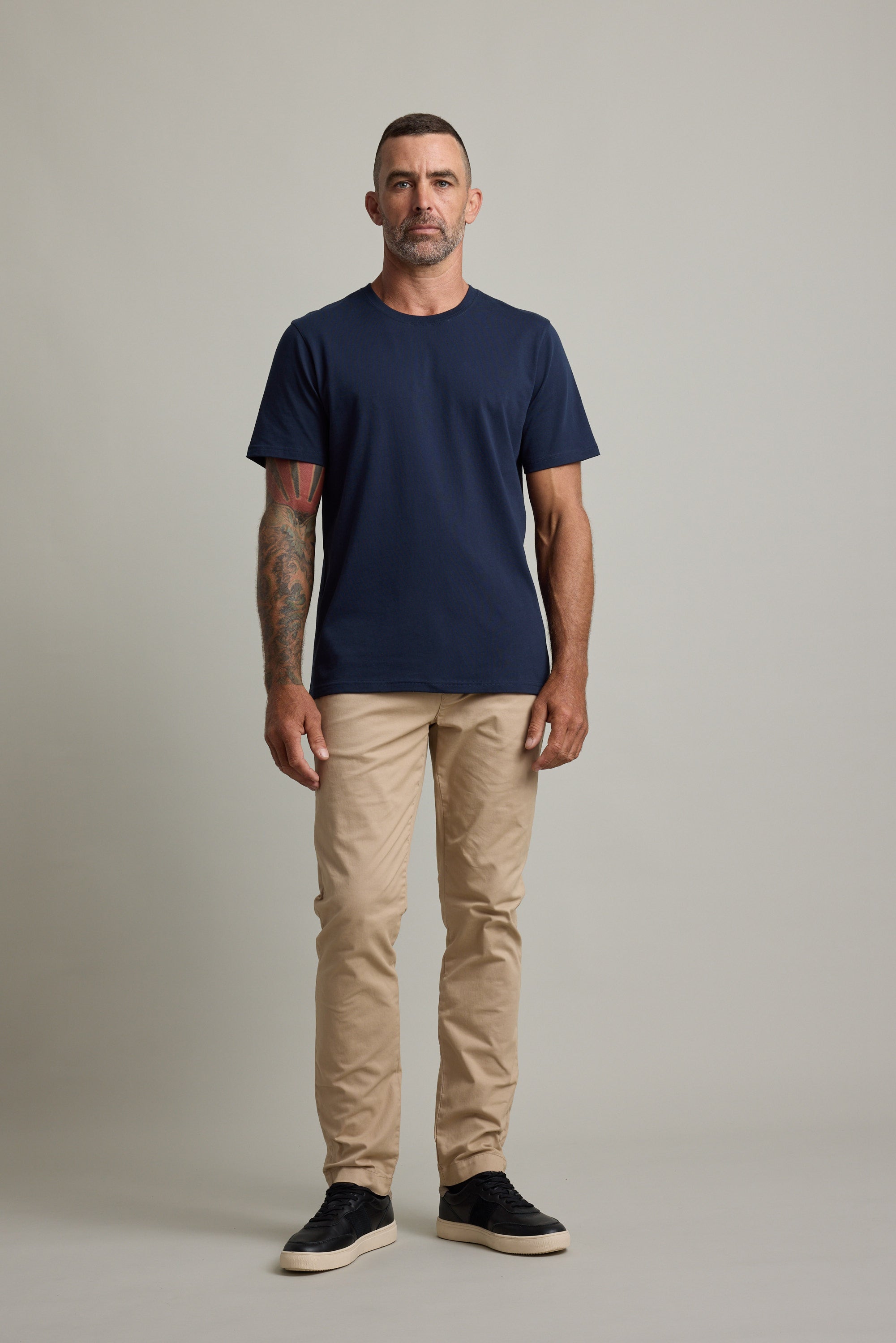 Man in a navy Barkers Good Earth Cotton Essential Tee and beige pants.