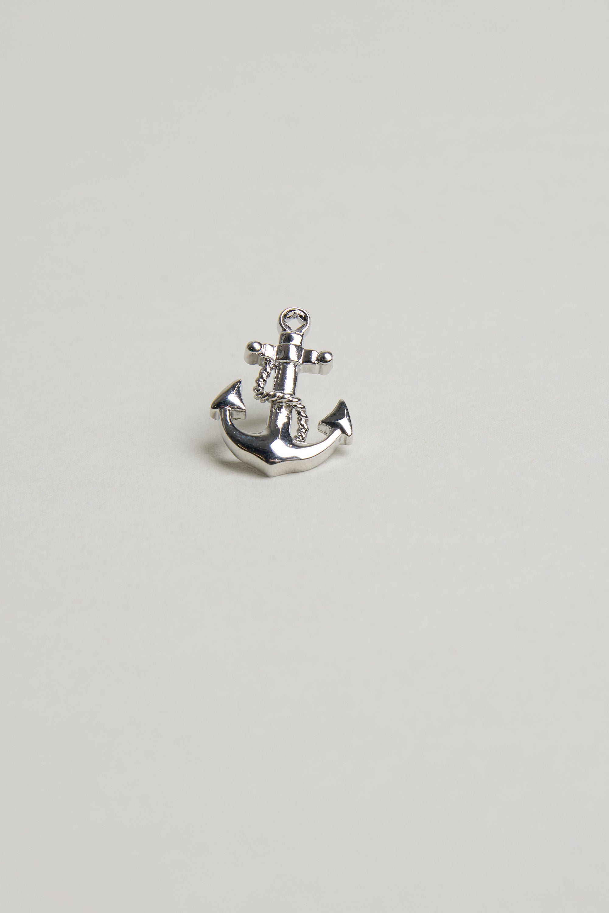 The Barkers Anchor Lapel Pin, a small shiny silver accessory shaped like an anchor, is displayed centered on a plain light gray background—ideal for nautical style or as a gift for ocean lovers.
