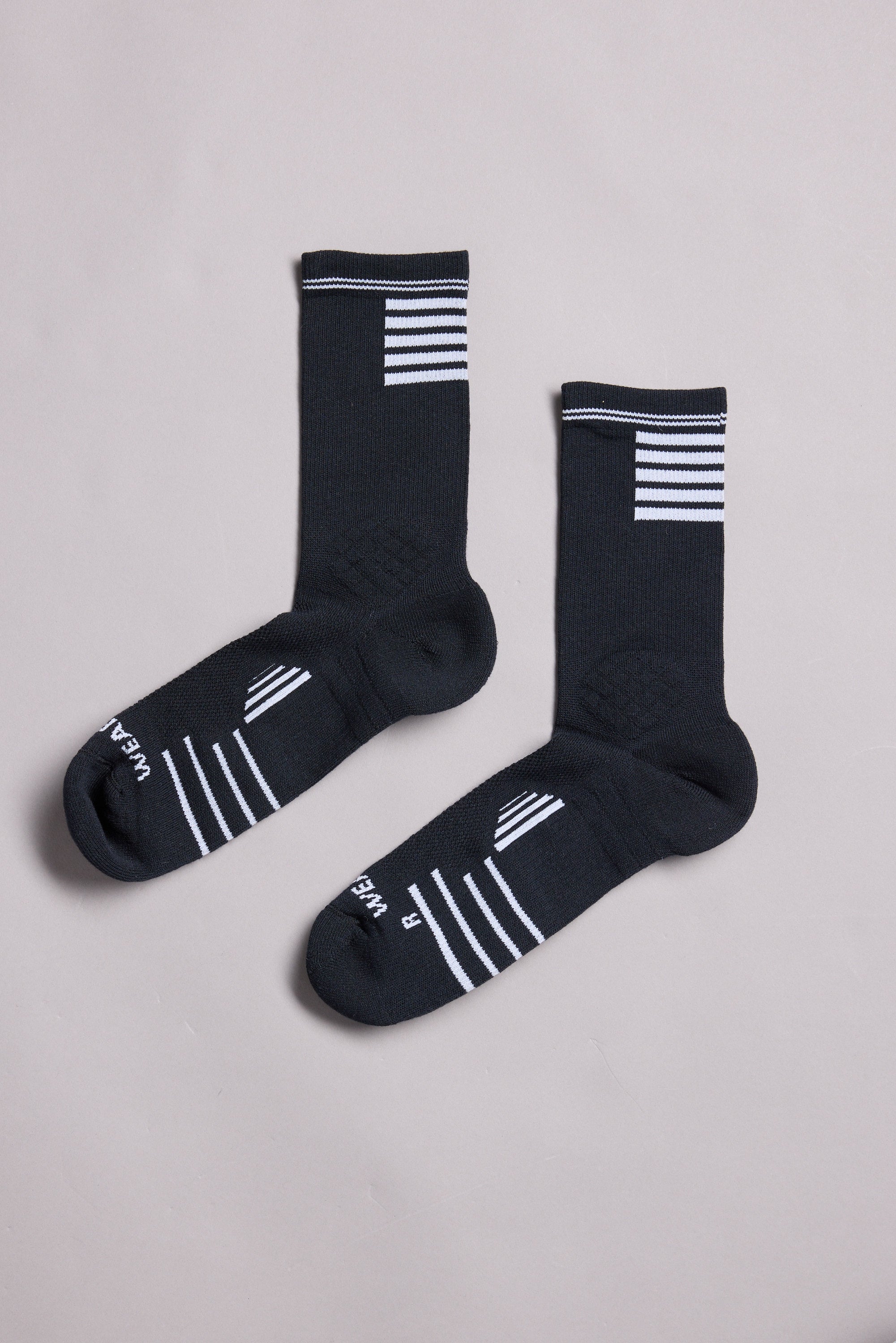 A pair of WearEver Active Socks by WearEver, made in New Zealand, in black with white stripes at the top and on the feet, labeled L and R for left and right, displayed on a plain light gray background.