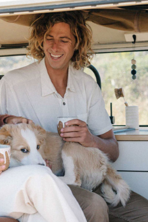 Man smiling with a dog on his lap, enjoying Other Smelly Balls: Cove / Coastal Drift scent.